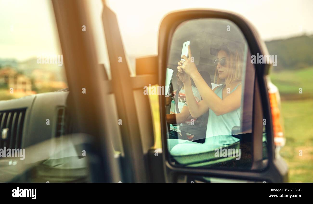 Riflessione in un camper furgone specchio retrovisore di una donna che prende una foto con il suo cellulare Foto Stock