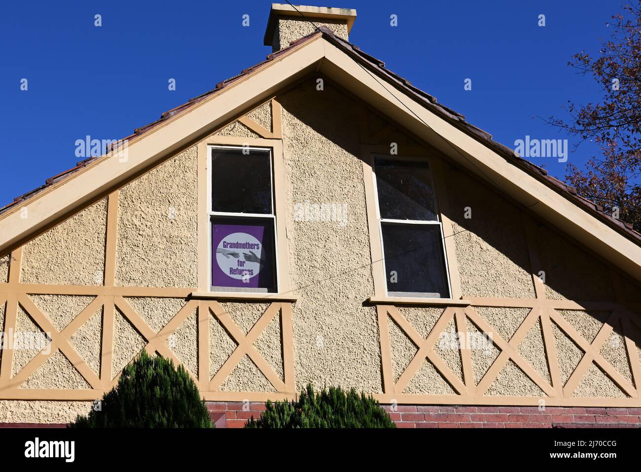 Il cartello viola "nonne per rifugiati" nella finestra al secondo piano di una casa suburbana Foto Stock