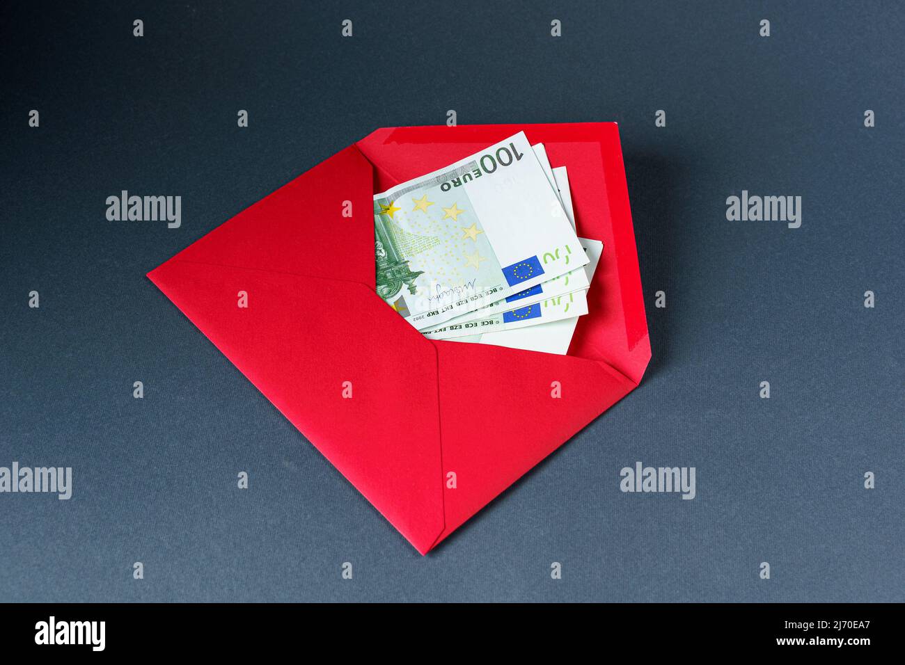 Busta di carta rossa aperta con cento banconote da euro su sfondo grigio. Foto Stock