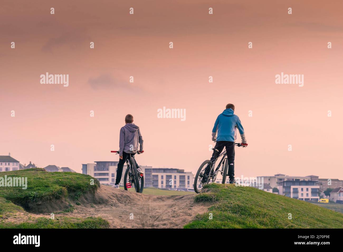 Due ragazzi in bicicletta su una pista sabbiosa a Fistral a Newquay in Cornovaglia. Foto Stock