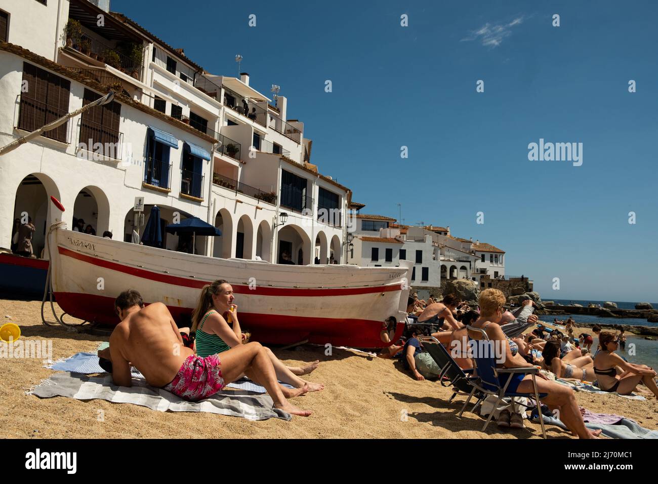 Calella de Palafrugell, Spagna - 25 aprile 2022: Barche da pesca e turisti sulla spiaggia di Port Bo, città vecchia di Calella de Palafrugell, in Costa Brava Foto Stock