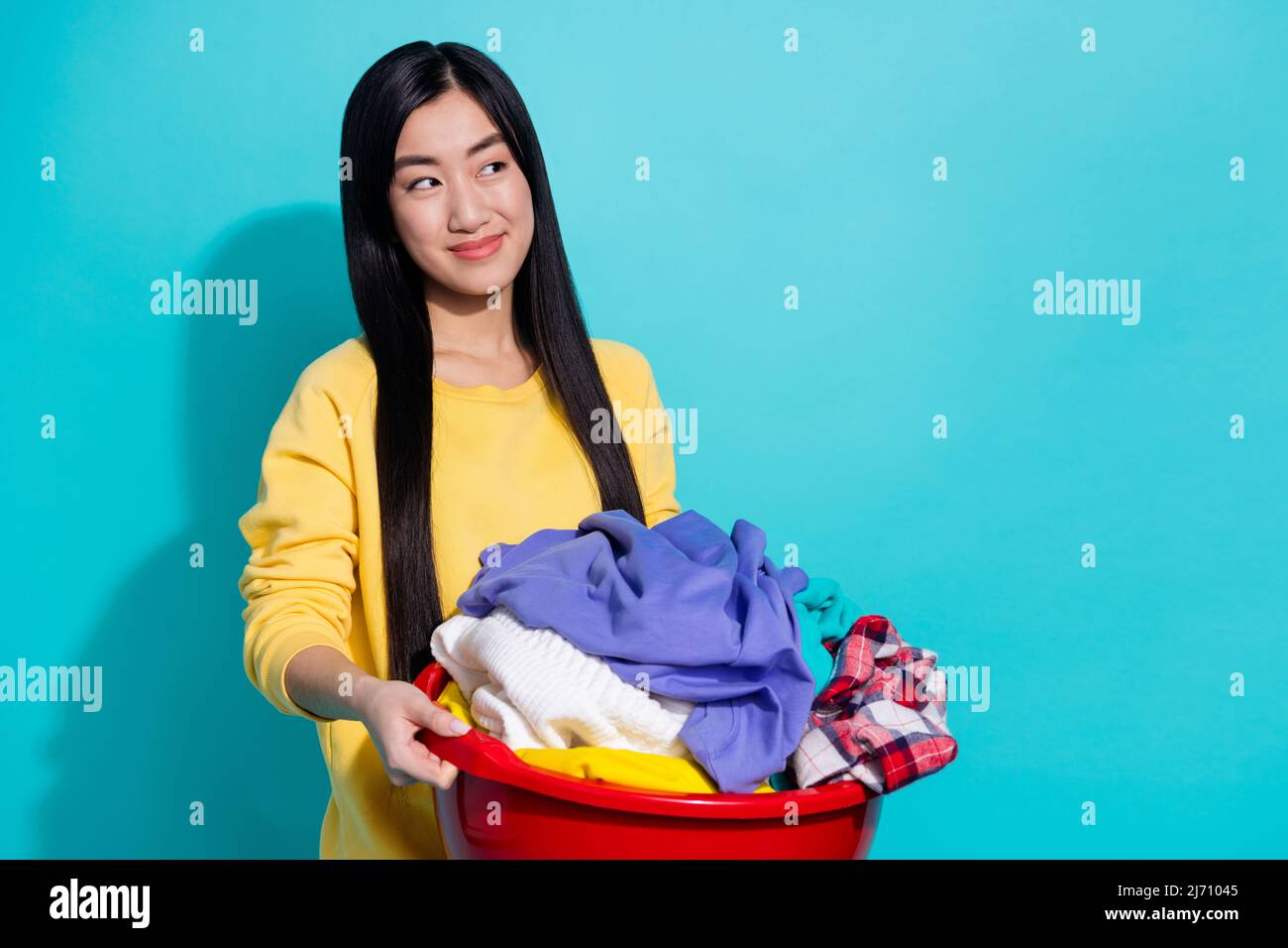 Foto di dolce bella signora vestito maglione giallo con una ciotola di lavanderia piena cercando spazio vuoto isolato turchese sfondo colore Foto Stock