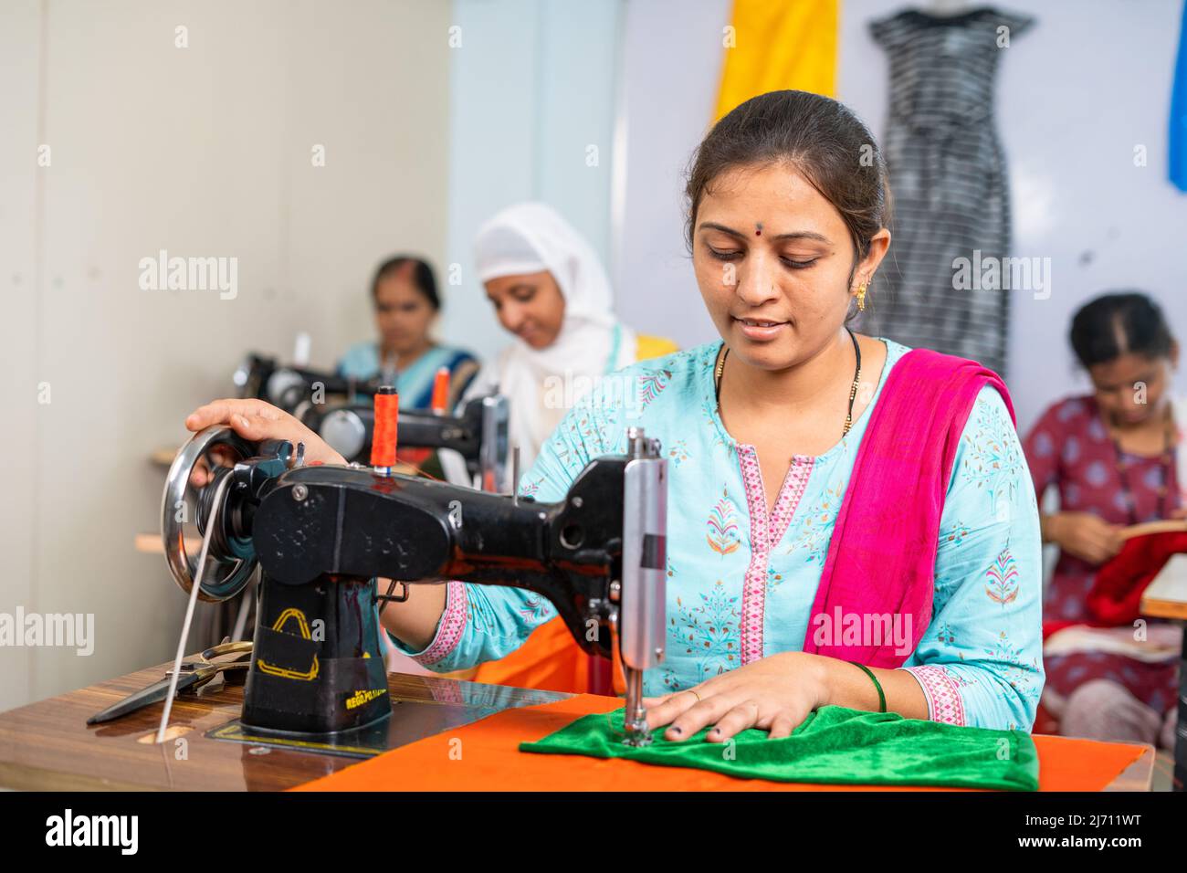 I dipendenti di abbigliamento sono impegnati a lavorare con il cucito di stoffa in fabbrica-concetto di lavoro duro, lavoratori autonomi e piccole imprese Foto Stock