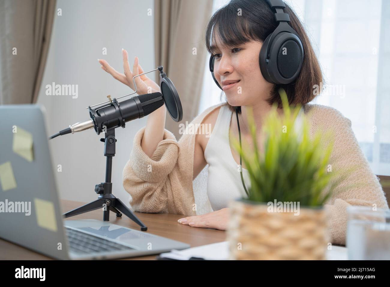 Donna che parla in modo espressivo con gesti delle mani in un microfono sulla scrivania. Foto Stock