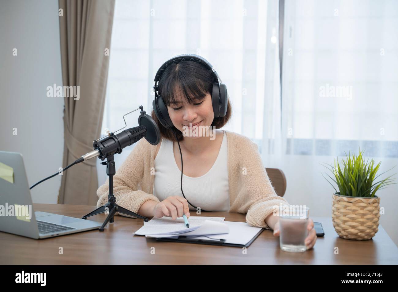 Donna che parla in modo espressivo con gesti delle mani in un microfono sulla scrivania. Foto Stock