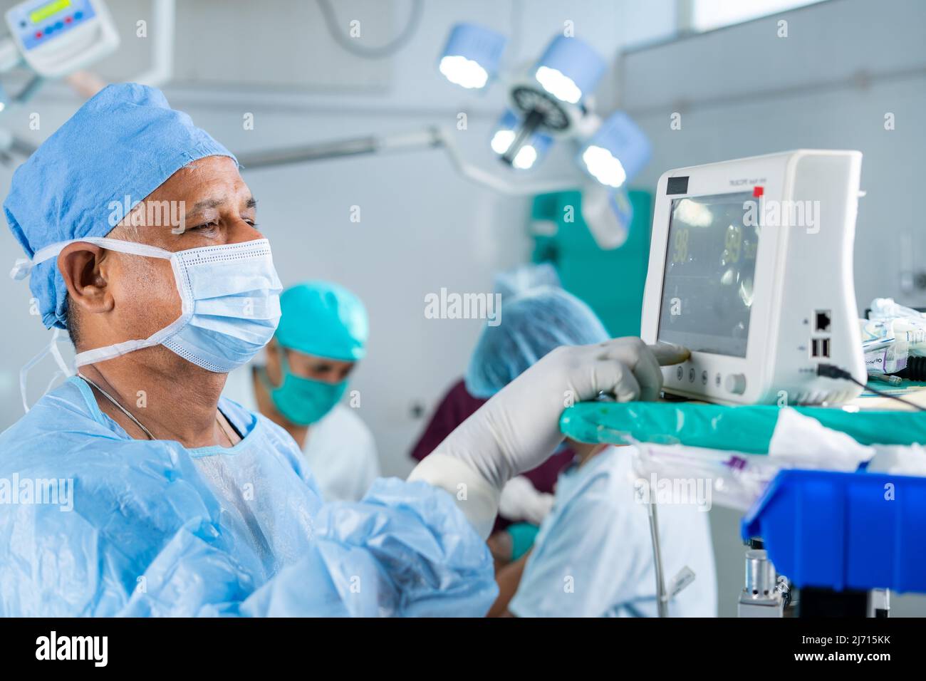 Chirurgo in uniforme che utilizza il monitor per il funzionamento al paziente in sala operatoria - concetto di tecnologia, assistenza sanitaria e trattamento Foto Stock