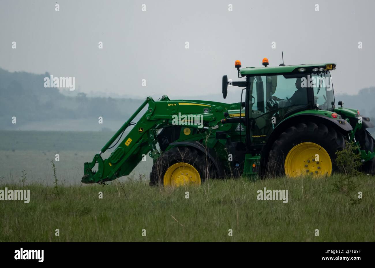 Trattore agricolo John Deere 6215R in movimento con sollevatore anteriore Foto Stock