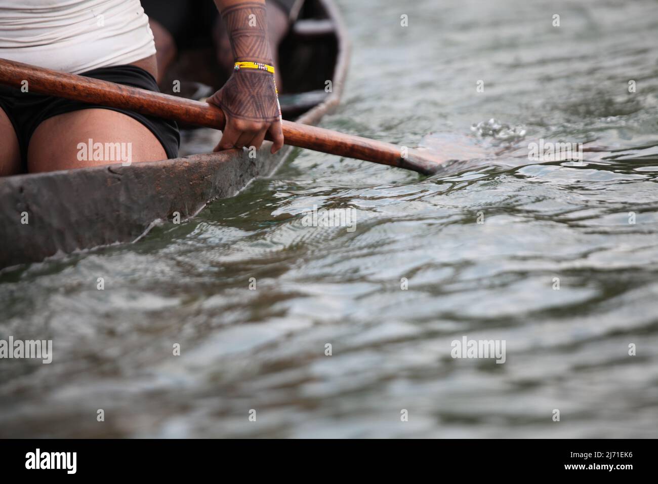 Particolare di una donna canottaggio, viaggiando su una rudimentale canoa di legno sul fiume Xingu, Amazzonia, Brasile. 2010. Foto Stock