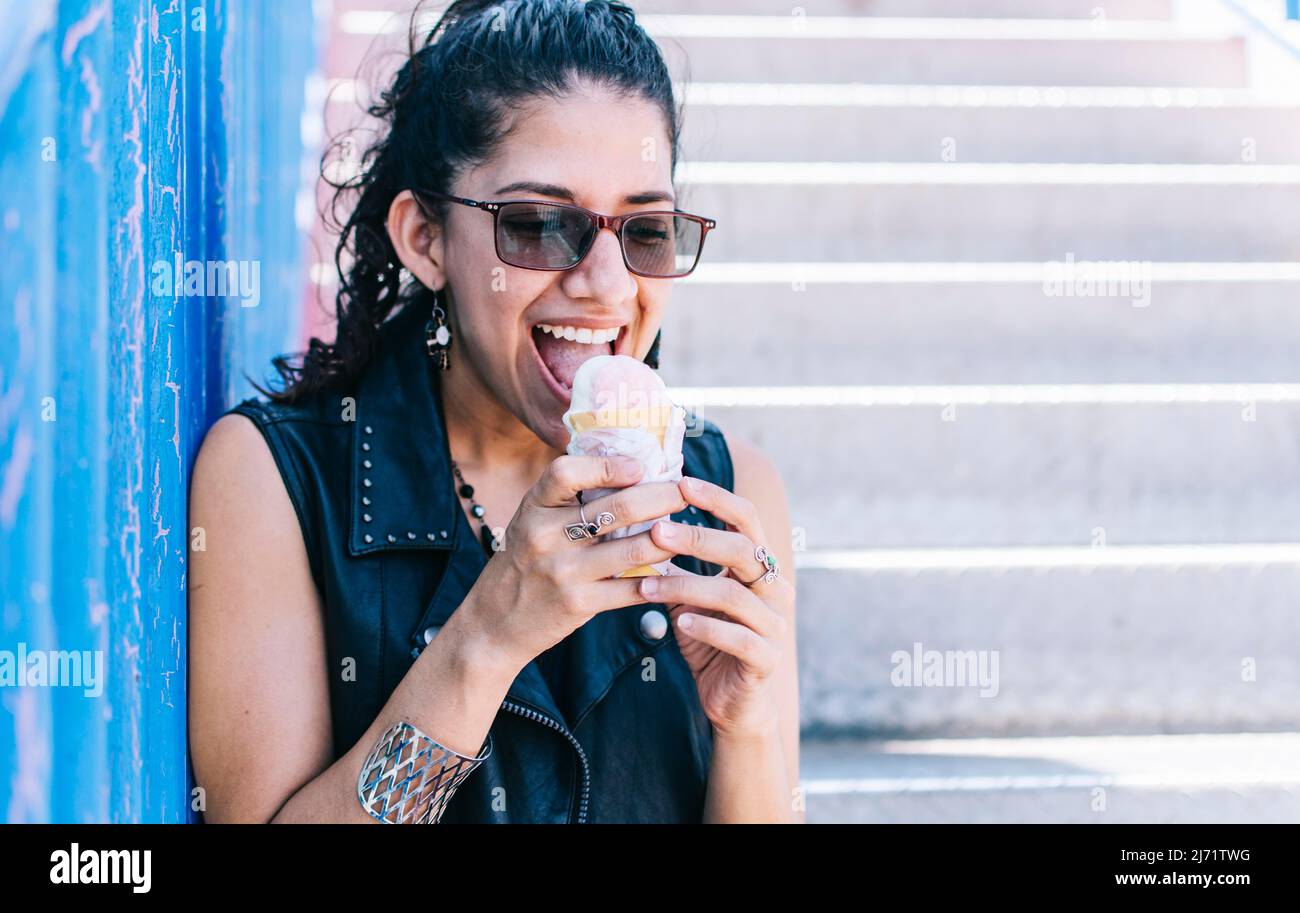 Urban ragazza che mangia un cono gelato, una ragazza che mangia un gelato all'aperto, una ragazza che gode di un gelato, un primo piano di una donna che tiene un gelato Foto Stock