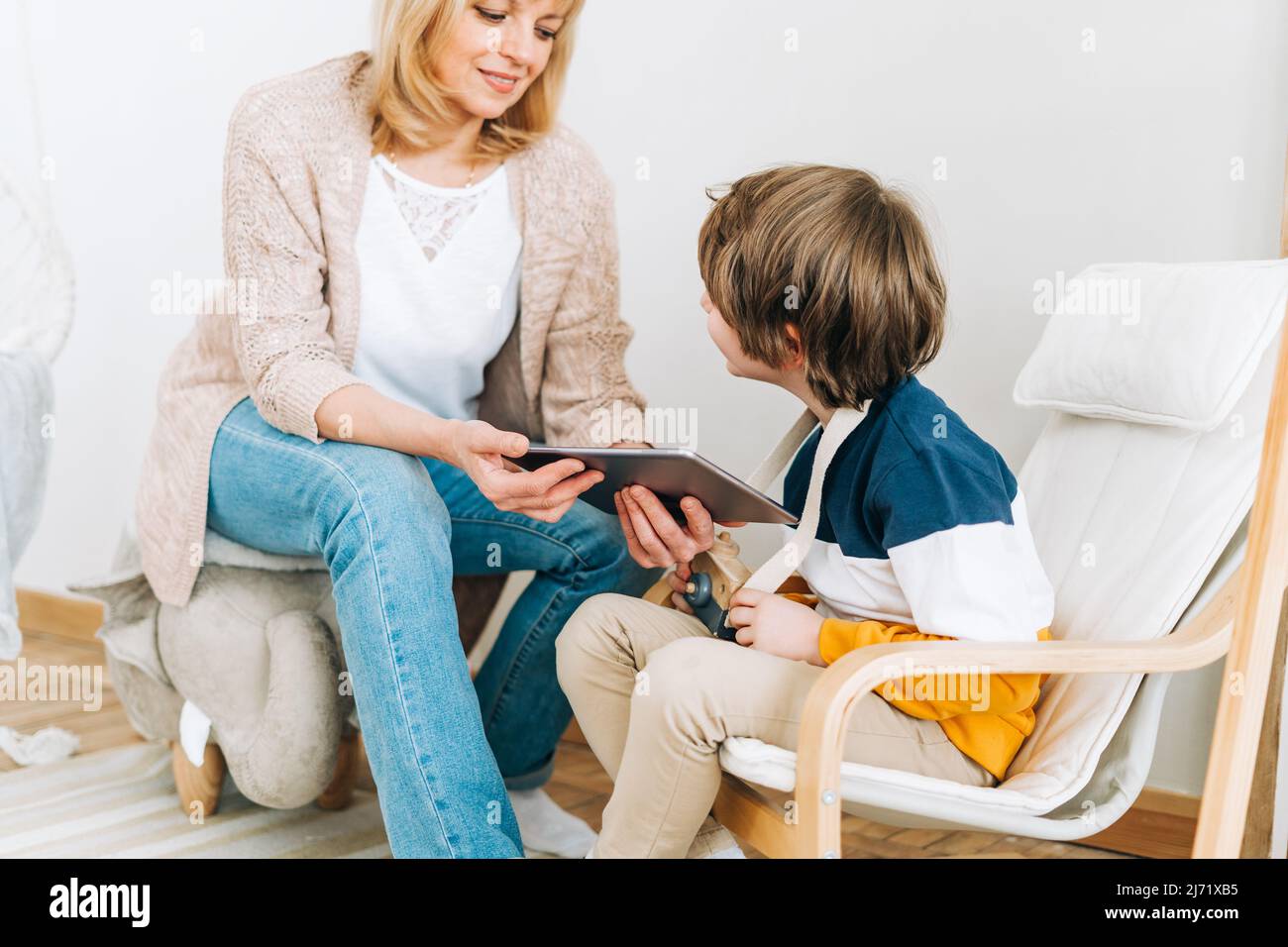 Buona nonna caucasica seduta con nipote a casa, guardando in un dispositivo tablet computer. La famiglia sorridente gioca i video giochi in linea con il ragazzo del capretto Foto Stock