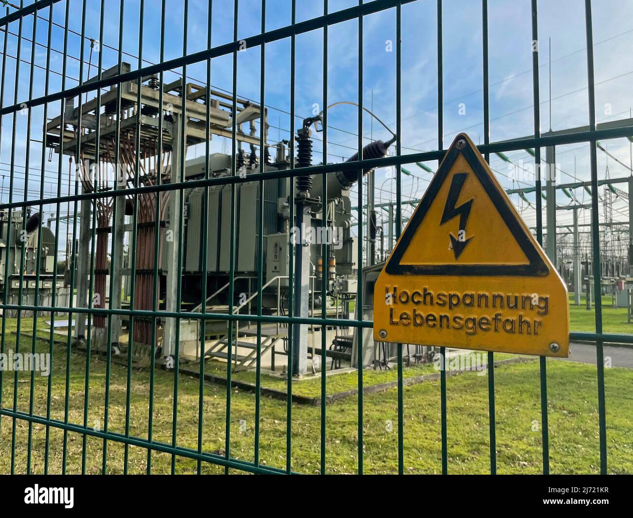 Sicherheitszaun mit Warnschild Hochspannung Lebensgefahr, dahinter Trafo in Umspannwerk fuer Stromversorgung, Nordrhein-Westfalen, Deutschland Foto Stock
