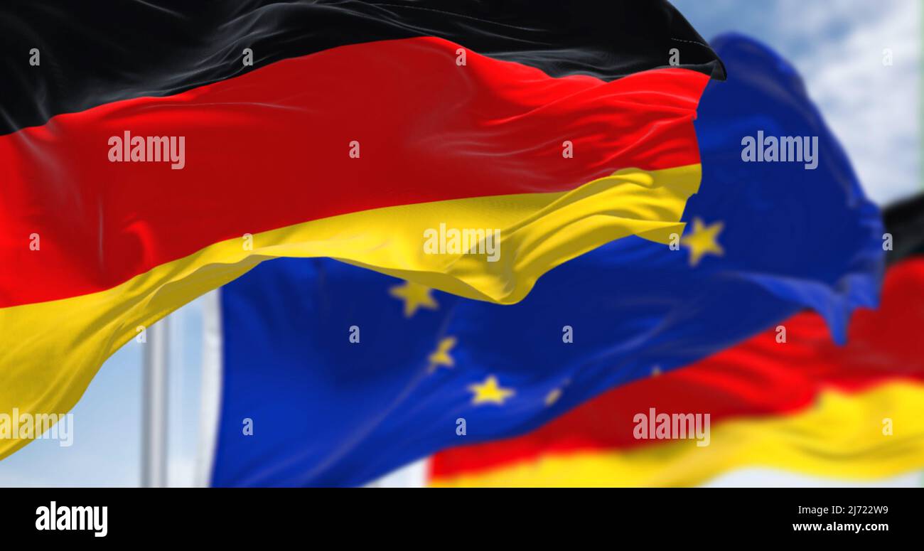 Dettaglio della bandiera nazionale della Germania che sventola nel vento con la bandiera dell'Unione europea sfocata sullo sfondo in una giornata chiara. Democrazia e politica. E Foto Stock