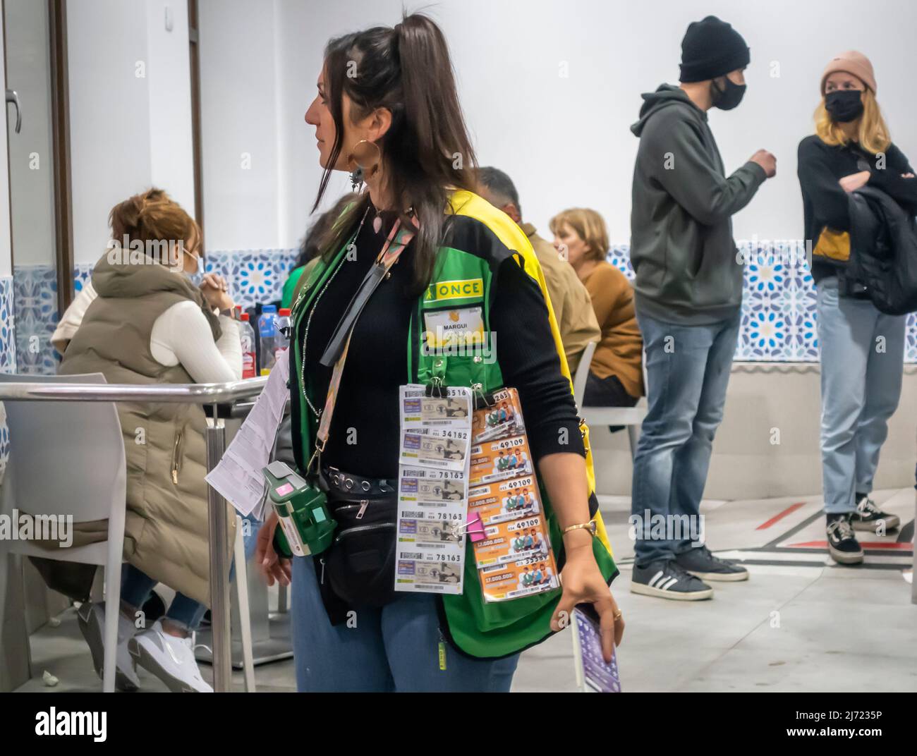 Venditore di biglietti della lotteria in un gilet con bocket della lotteria in un caffè locale. Granada, Andalusia, Spagna Foto Stock