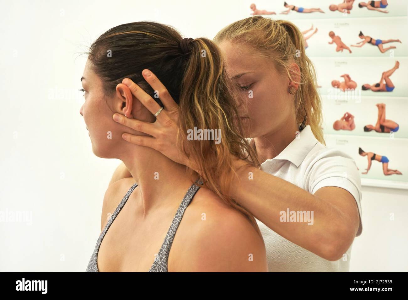 Giovane fisioterapista che si esercita con la sua paziente femminile, fissando testa e collo con la mano, durante l'esercizio Foto Stock