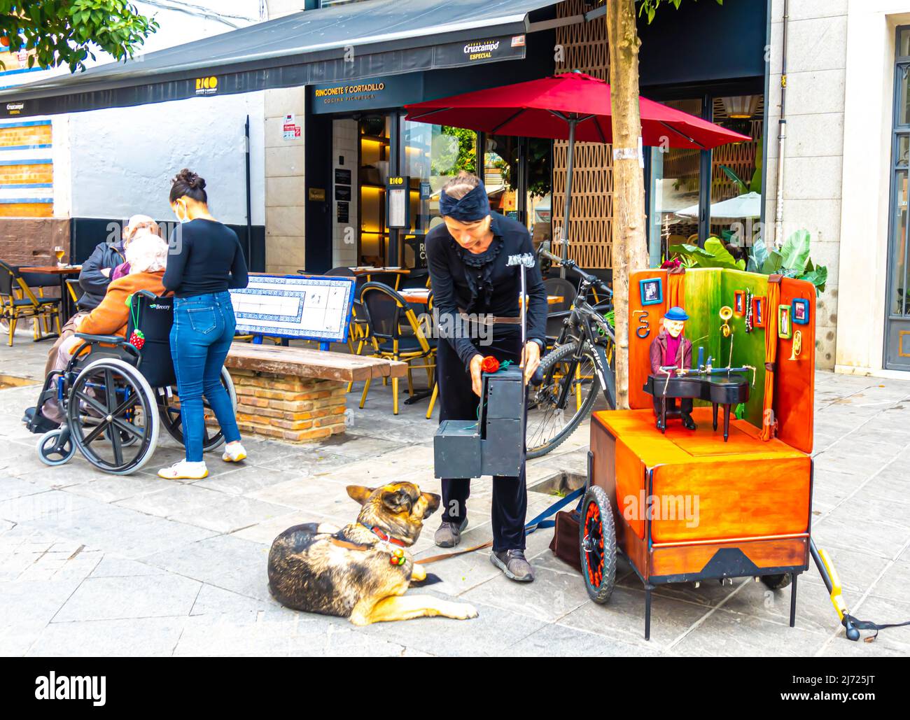 L'intrattenitore di strada con mobile music box e il suo cane in C San Jacinto, Triana, Siviglia, Andalusia, Spagna Foto Stock