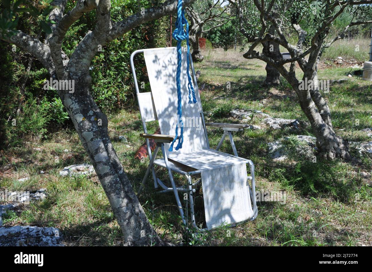 Sedia pieghevole campeggio si trova nel giardino sul prato in una giornata estiva soleggiato. Vecchia sedia estate campeggio. Foto Stock