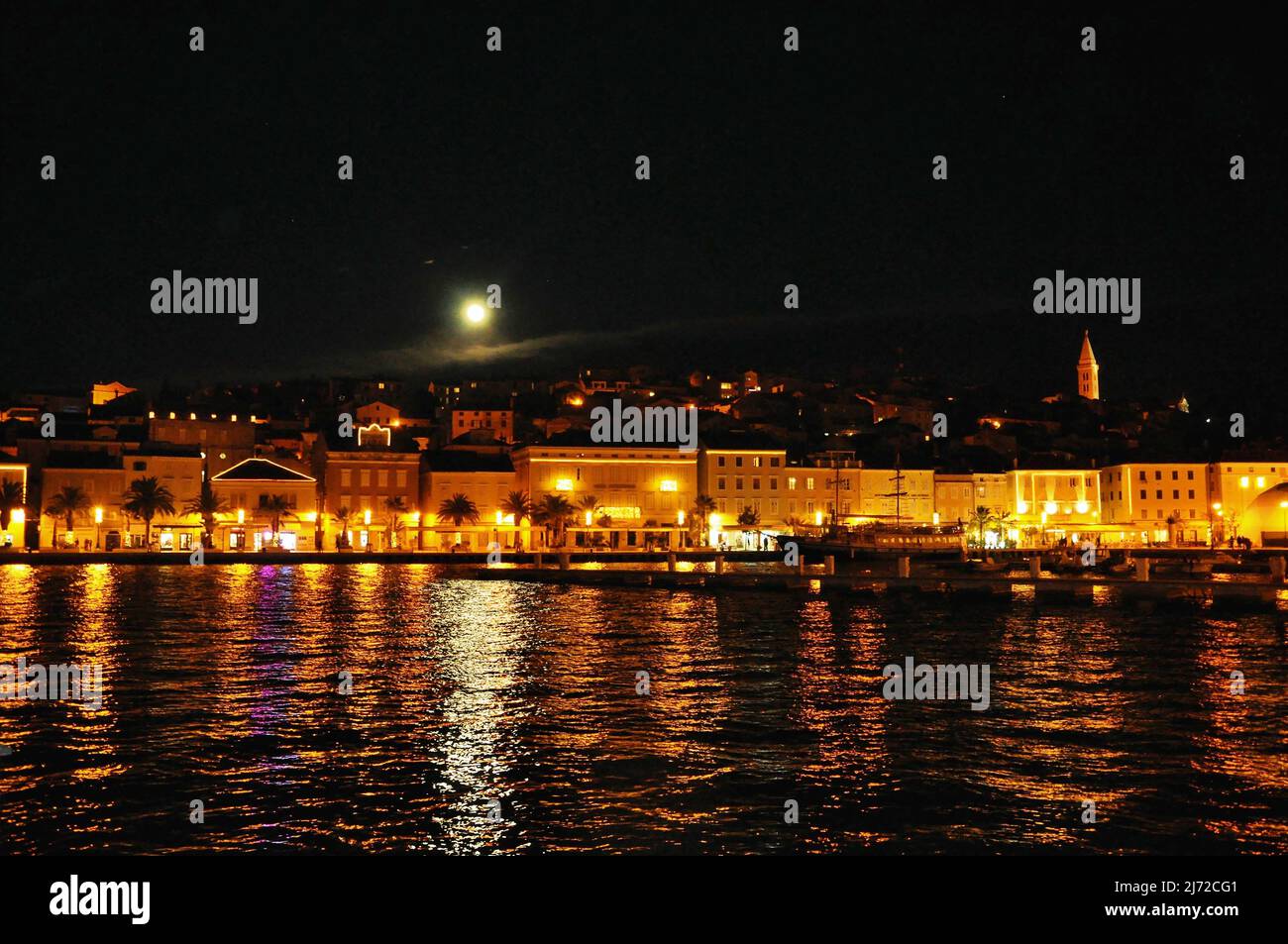 Città di Lussinpiccolo in scena notturna presa dal mare in modo che la luce si rifletta sul mare. Mali Losinj costa di notte, Croazia famosa destinazione turistica. Foto Stock