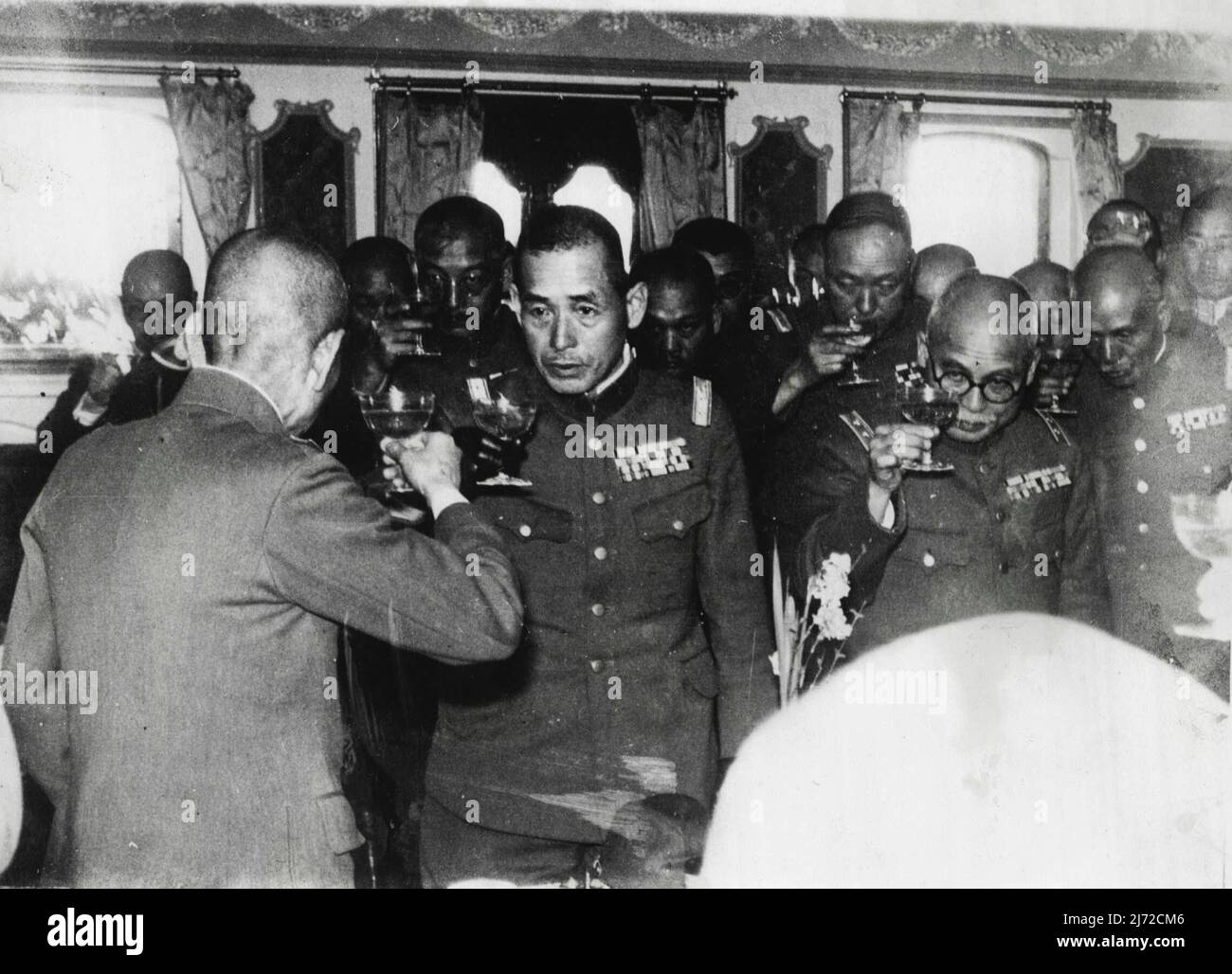 Ritirando il capo dell'esercito giapponese lascia Shanghai -- bordo il trasporto militare giapponese su cui il generale Matsui, ex comandante-in-capo delle forze giapponesi ha lasciato Shanghai per il Giappone. Gli ufficiali giapponesi sono visti bere un brindisi di addio al 'piccolo Napoleone' del Giappone. Il generale Shunroku Hata, il nuovo Comandante in Capo (guardando la macchina fotografica) è visto tostare il generale Iwane Matsui (ritorno alla macchina fotografica). Marzo 23, 1938. (Foto di Keystone). Foto Stock