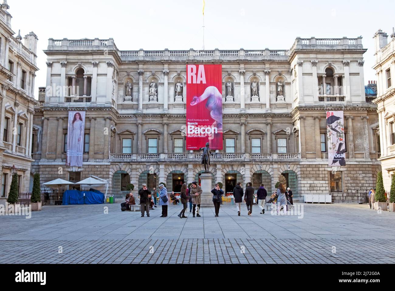 Vista esterna della Royal Academy of Art Building, il pittore britannico Francis Bacon banner e la gente nel cortile Aprile 2022 Londra UK KATHY DEWITT Foto Stock