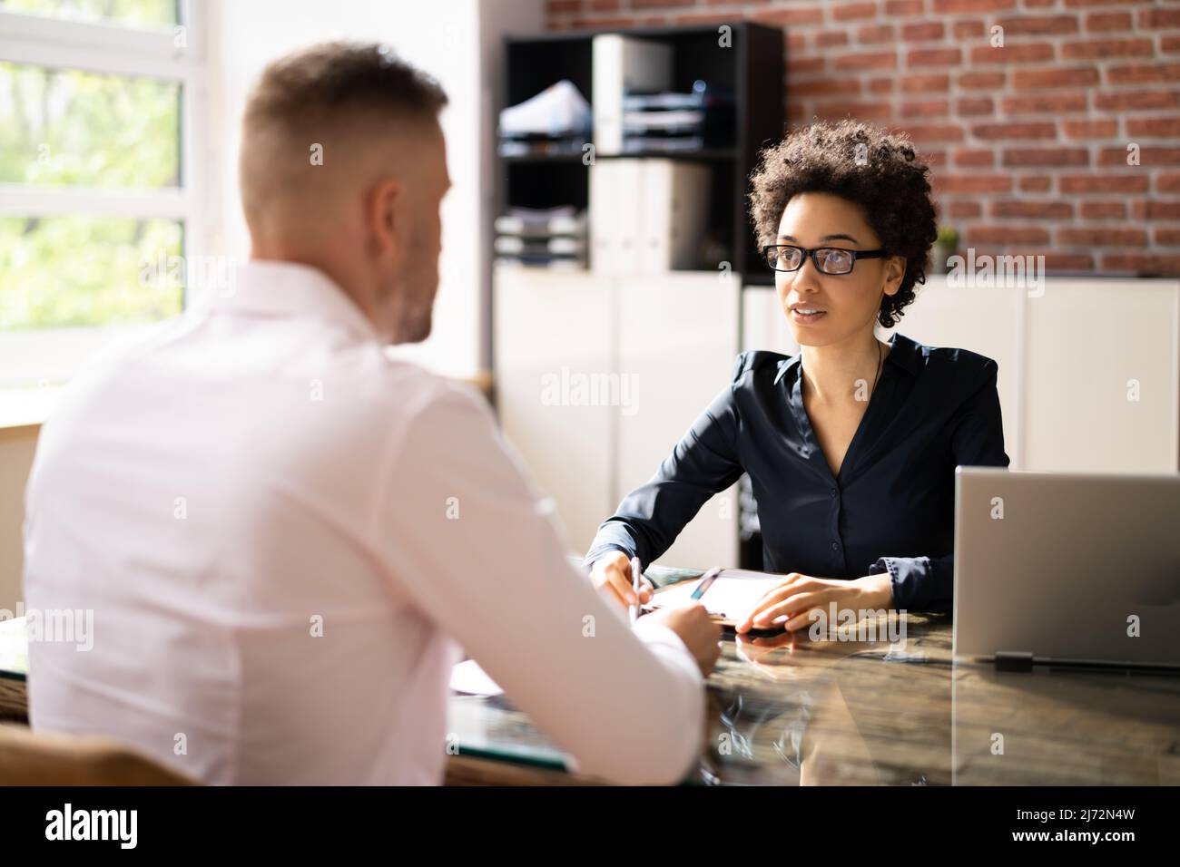 Responsabile femminile intervistando UN giovane candidato maschio in ufficio Foto Stock