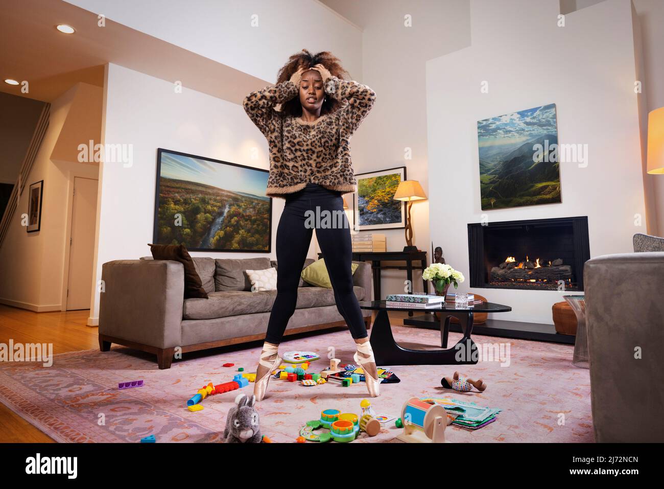 Ballerina femminile tra mare di giocattoli in soggiorno. Foto Stock