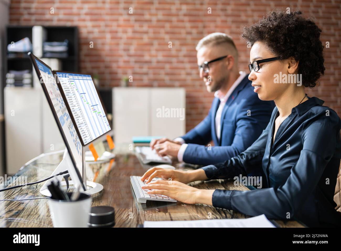 Giovani Imprenditori analizzando diagramma di Gantt e Calendario sul computer in ufficio Foto Stock