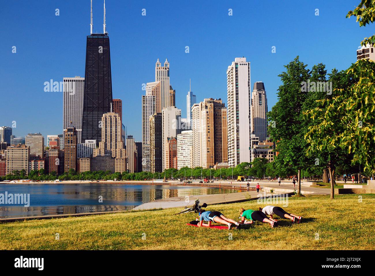Tre donne si esercitano lungo il lungolago in vista dello skyline di Chicago in una soleggiata giornata estiva Foto Stock