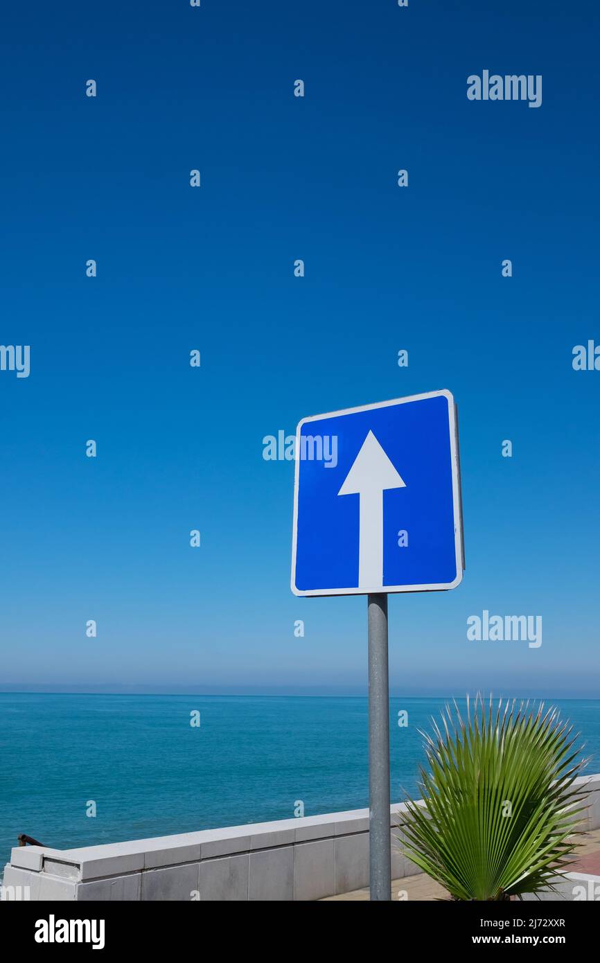 Cartello stradale quadrato con freccia bianca su sfondo cielo blu. Indica  una strada a senso unico Foto stock - Alamy