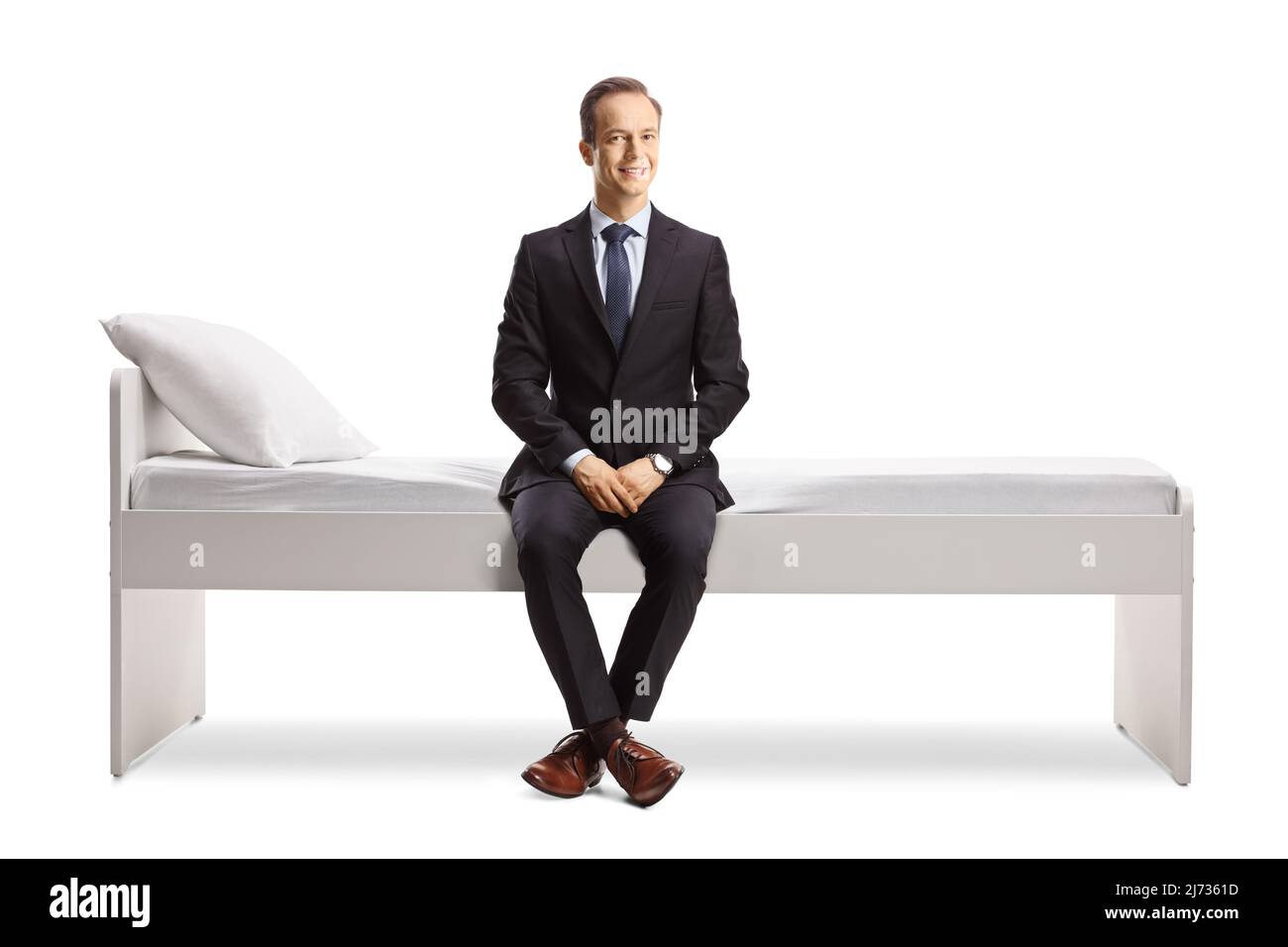Uomo professionista in un abito e cravatta seduta su un letto isolato su sfondo bianco Foto Stock