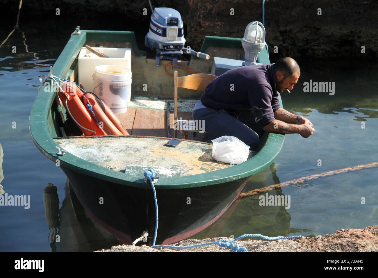 Uomo in una barca da pesca ormeggiata nel sud Italia Foto Stock
