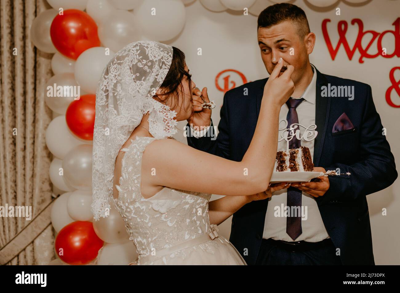 sposare e sposare a matrimonio tagliare il loro grande multi-tiered torta bianca gusto che si nutrì l'uno dall'altro. Tradizione russa Slavica Ucraina Foto Stock