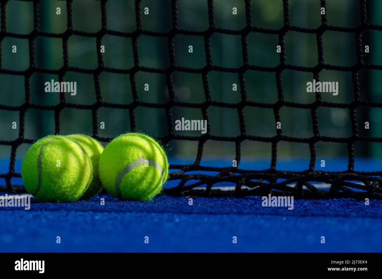 campo da tennis con paddle blu, tre palle vicino alla rete Foto Stock