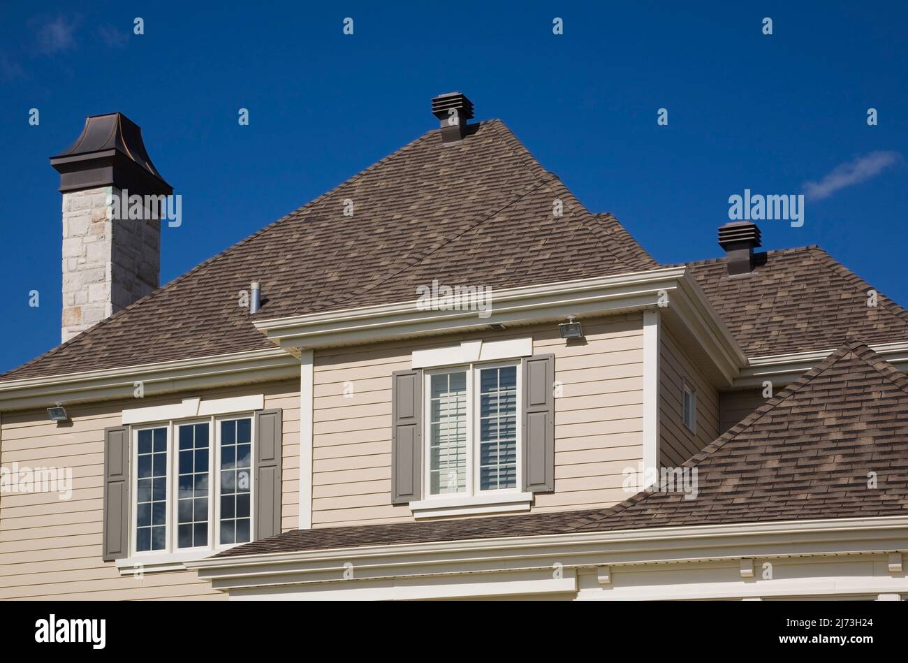 Vista parziale dei tetti in ghiaia di asfalto marroni a più livelli su una casa di lusso a due piani. Foto Stock