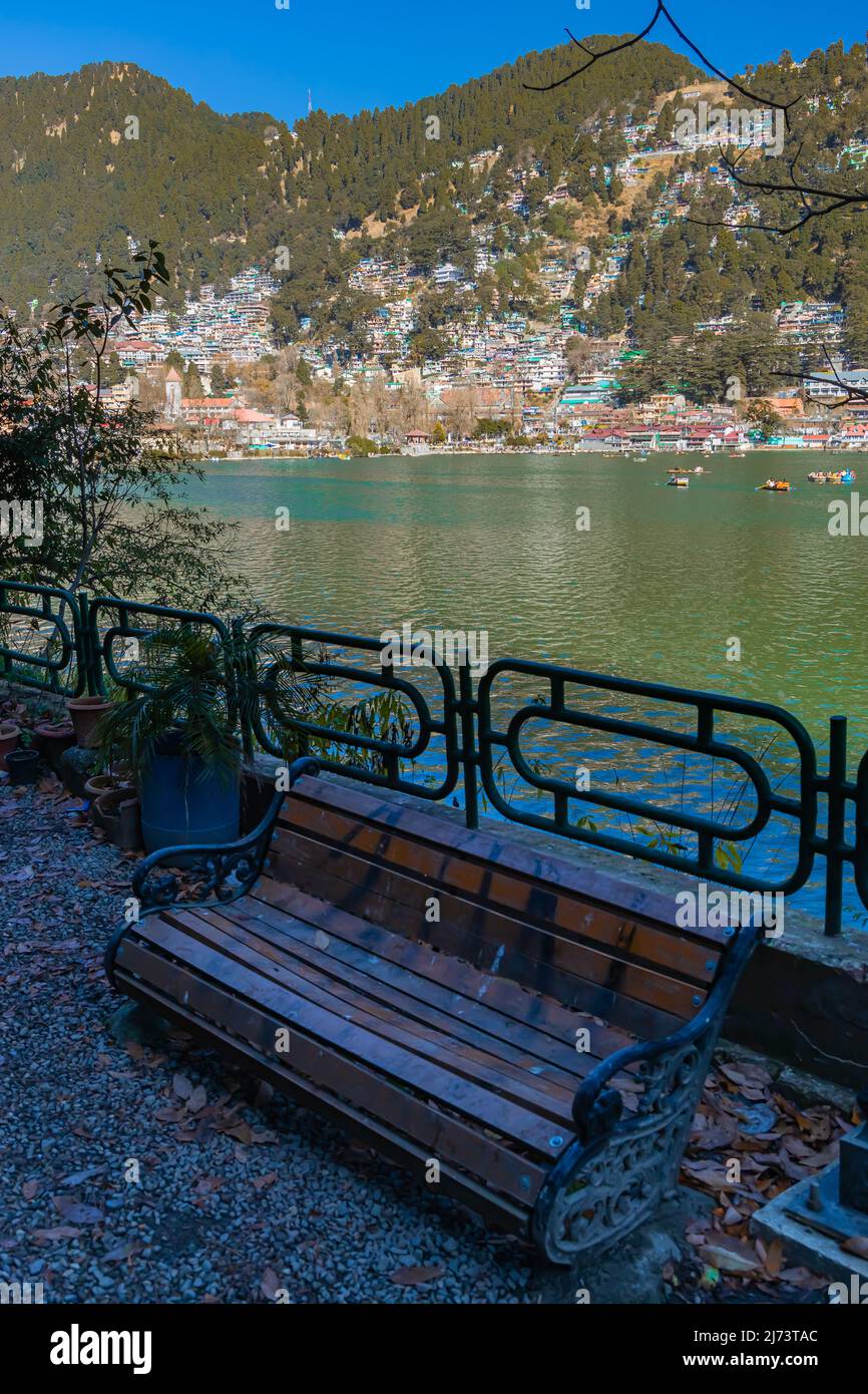 Una panchina posta in un tranquillo giardino a lato del lago con la vista sul lago sul suo retro Foto Stock