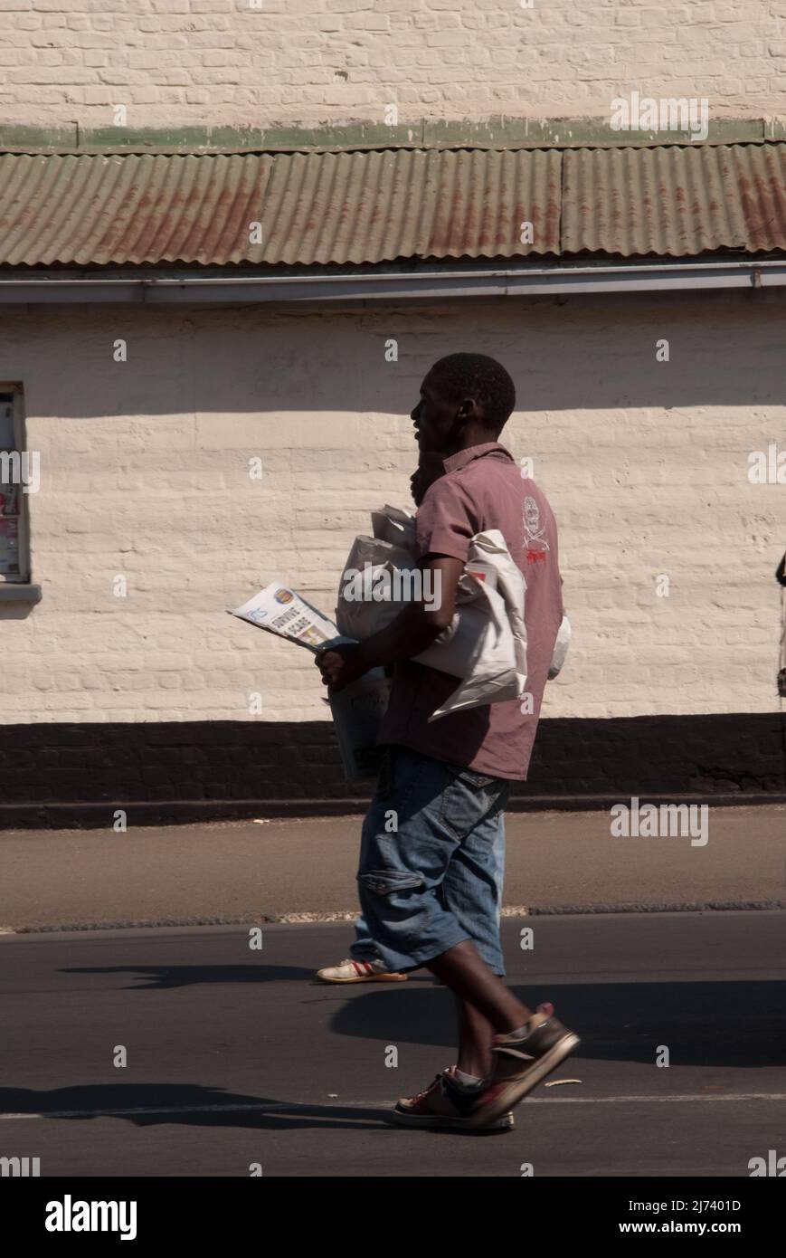 Ragazzi che vendono giornali, fuori da un vecchio edificio amministrativo, Blantire, Malawi, Africa. Blantyre (che prende il nome dal luogo di nascita di David Livingstone a SCO Foto Stock