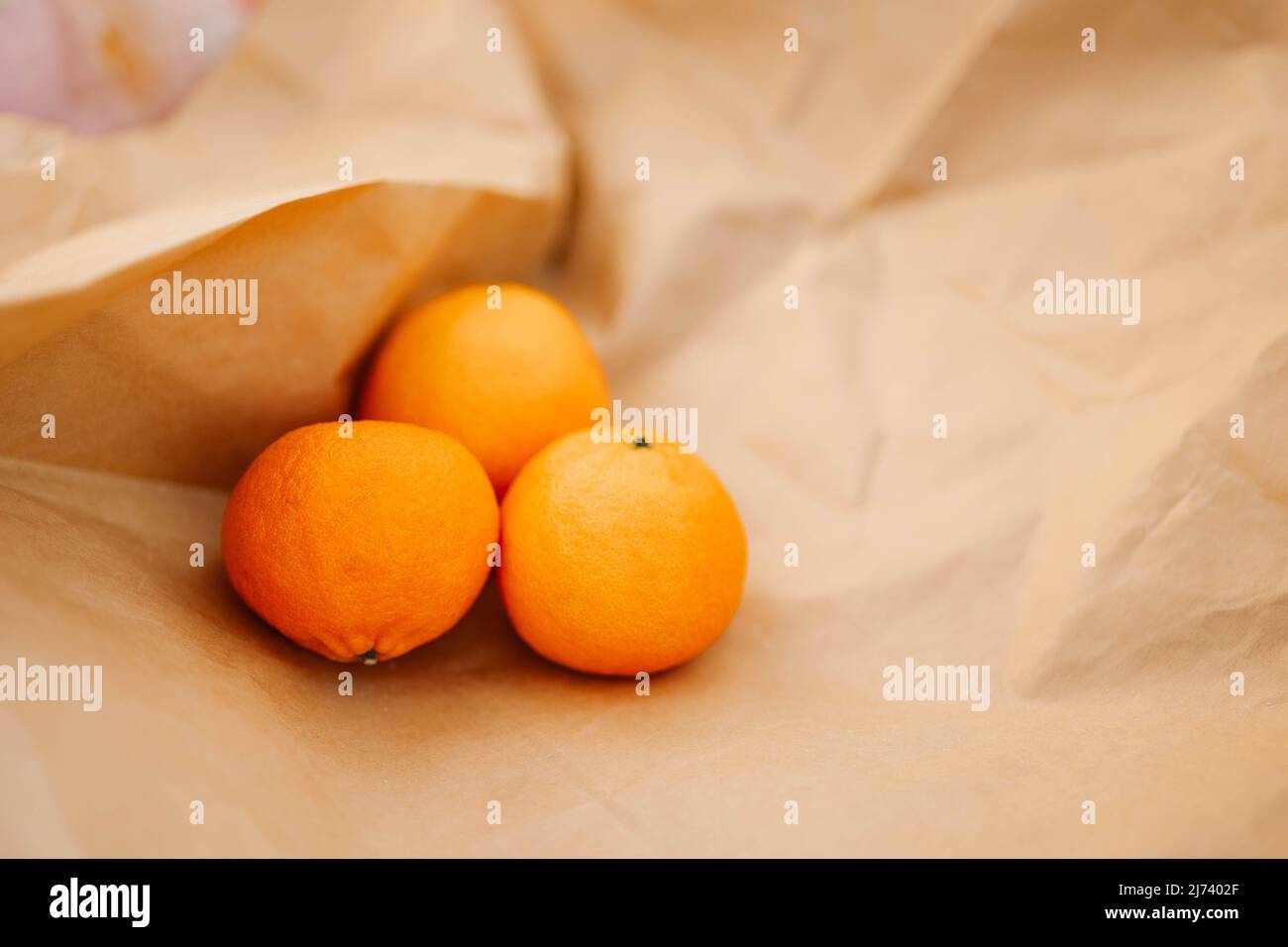 Le arance di agrumi giacciono sulla carta artigianale. Tangerini fragranti. Foto di alta qualità Foto Stock