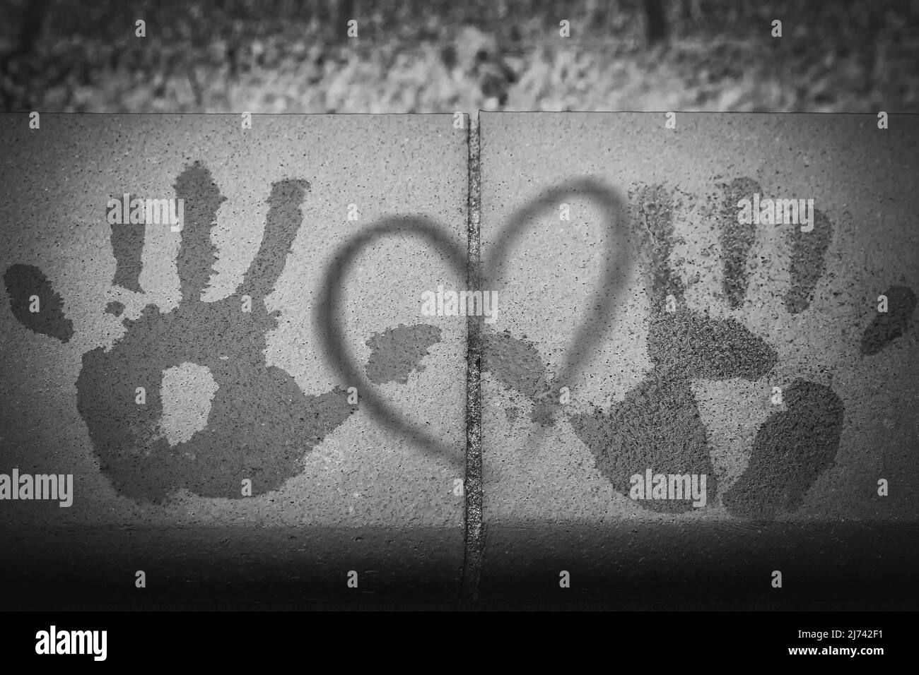 Le stampe di due mani su un muro con un cuore al centro, in bianco e nero Foto Stock