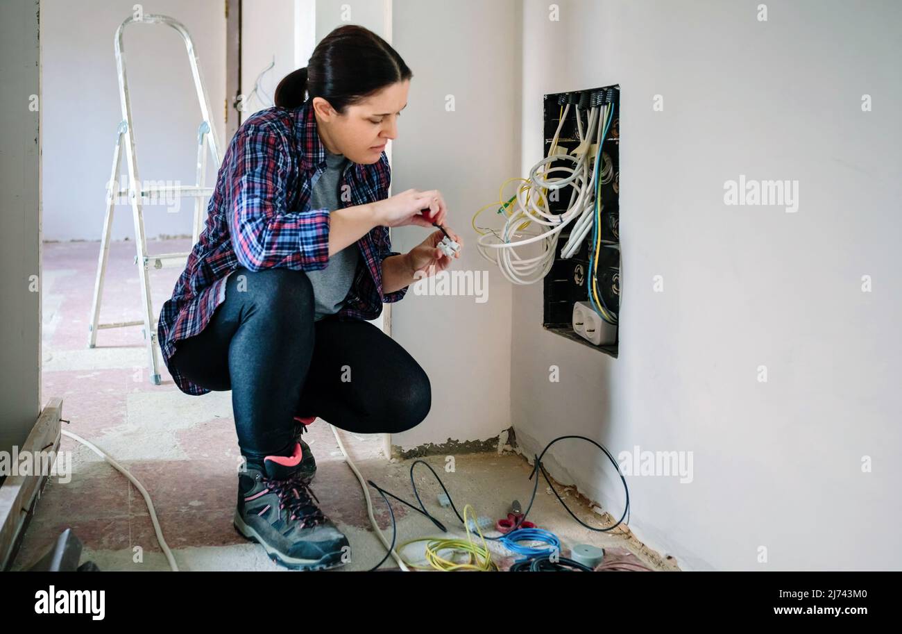 Tecnico con cacciavite e morsettiera per l'installazione della scatola per telecomunicazioni Foto Stock