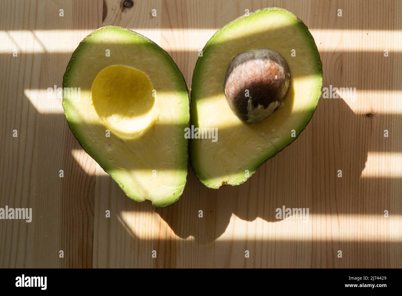 Avocado su sfondo in legno. Avocado frutta. Frutta cruda sano cibo verde. Metà avocado. Foto Stock
