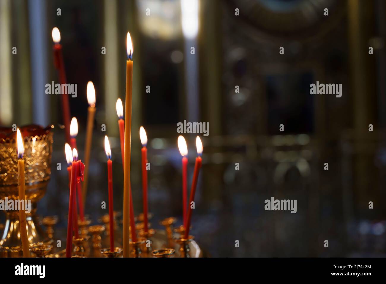 Candele in uno sfondo cristiano-ortodosso chiesa. Fiamma di candele nell'oscuro e sacro interno del tempio. Foto di alta qualità Foto Stock