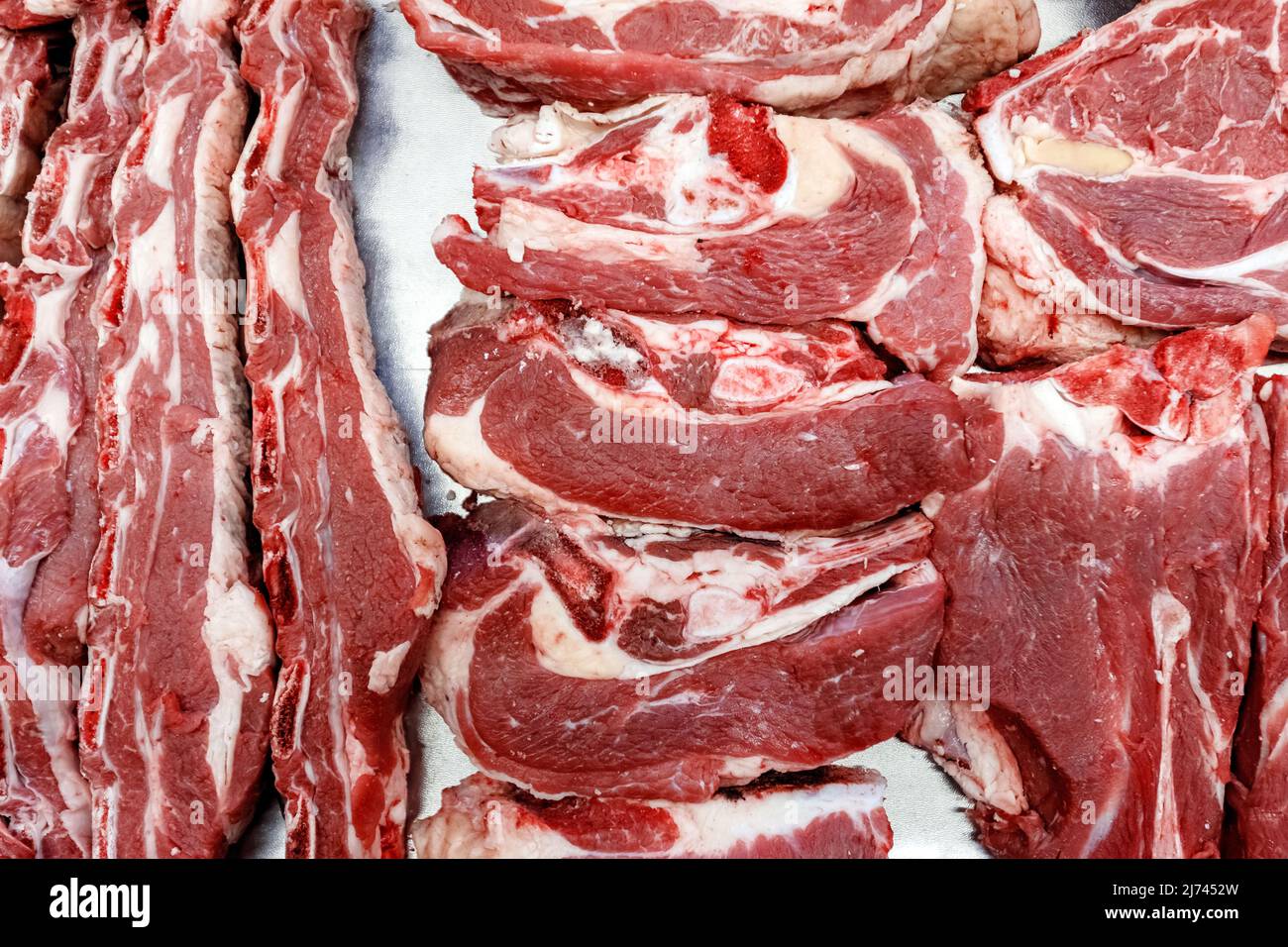 Vista dall'alto di pezzi di manzo fresco con grasso che giacciono sul bancone al mercato del villaggio. Foto Stock