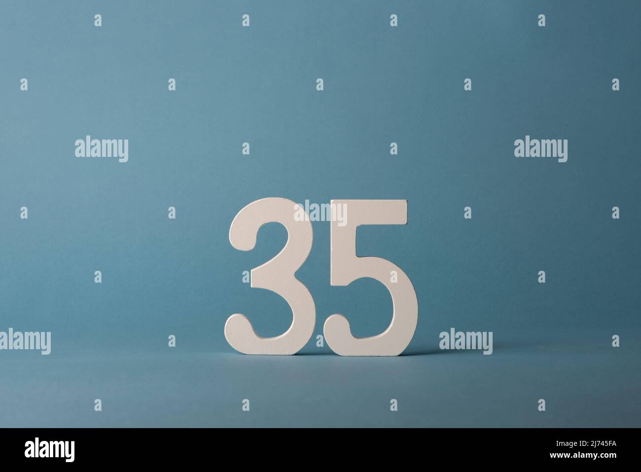 Numero di legno bianco trentacinque 35 su sfondo blu. Foto Stock
