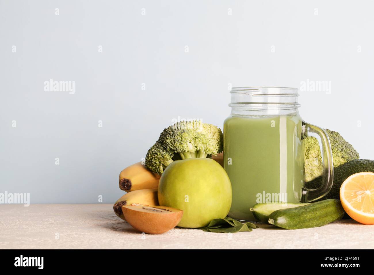 Frullato verde fresco in bottiglia di vetro con verdure su sfondo blu.vegan cibo, cura di sé e lifestyle.sano dieta detox Foto Stock