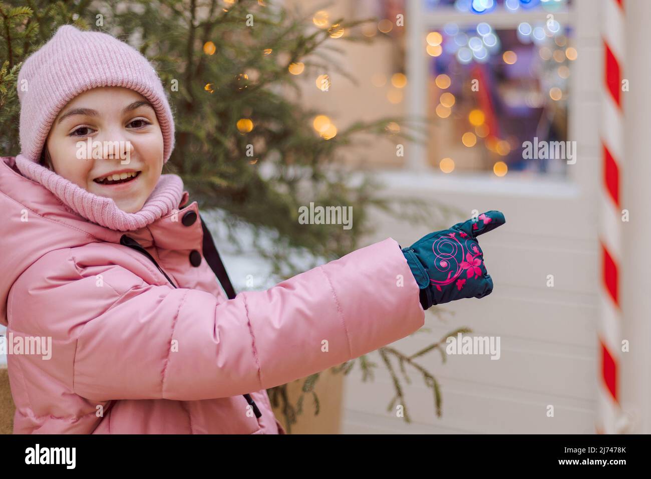 Piccola ragazza felice in rosa alla fiera di Natale. La gente compra i regali per la festa al mercato di Natale. Foto di alta qualità Foto Stock