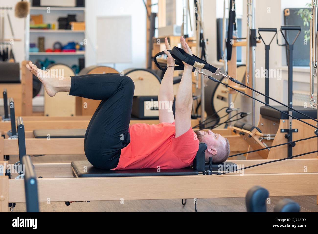 L'allenatore di pilates per il fitness maschile mostra esercizi su simulatori speciali. Pilates Stretch Tables. Foto di alta qualità Foto Stock