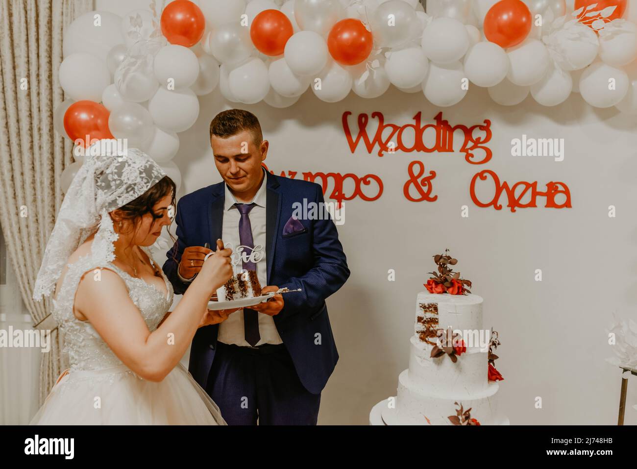 sposare e sposare a matrimonio tagliare il loro grande multi-tiered torta bianca gusto che si nutrì l'uno dall'altro. Tradizione russa Slavica Ucraina Foto Stock