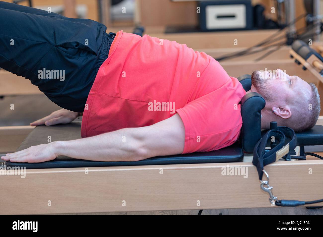 L'allenatore di pilates per il fitness maschile mostra esercizi su simulatori speciali. Pilates Stretch Tables. Foto di alta qualità Foto Stock