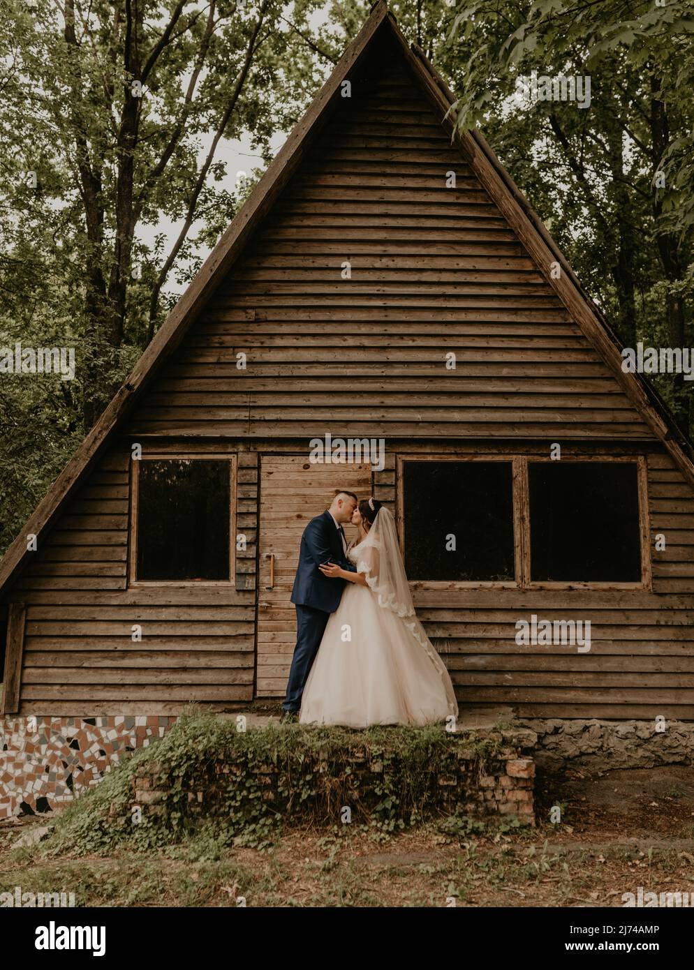 Giovane uomo caucasico europeo sposare in abito blu e donna dai capelli neri sposare in abito da sposa bianco con velo lungo e tiara sulla testa. Sposi novelli Foto Stock
