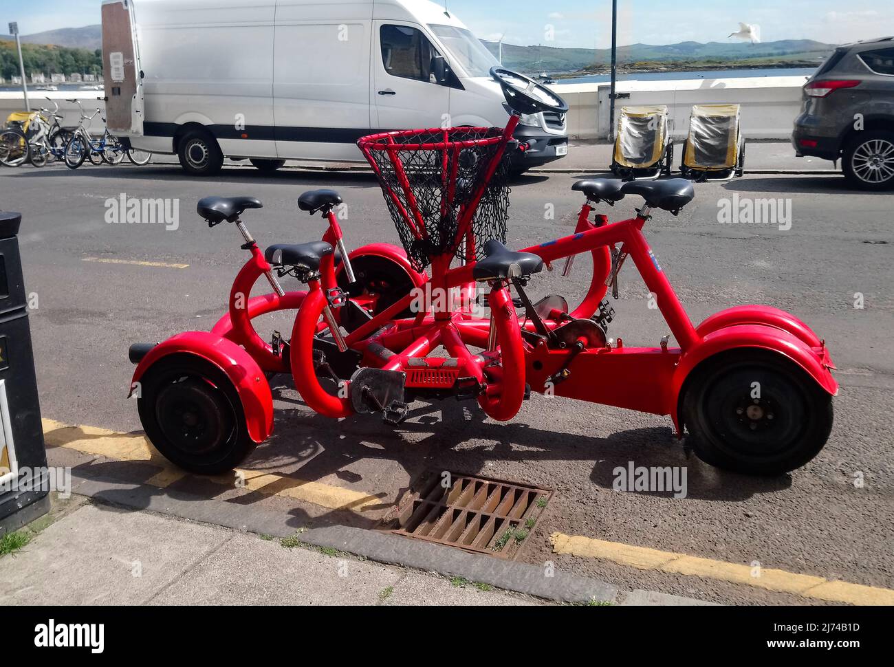 E strana e insolita bicicletta rossa a sette posti con volante avvistato sull'isola di Cumbrae, Scozia in 2019.j Foto Stock
