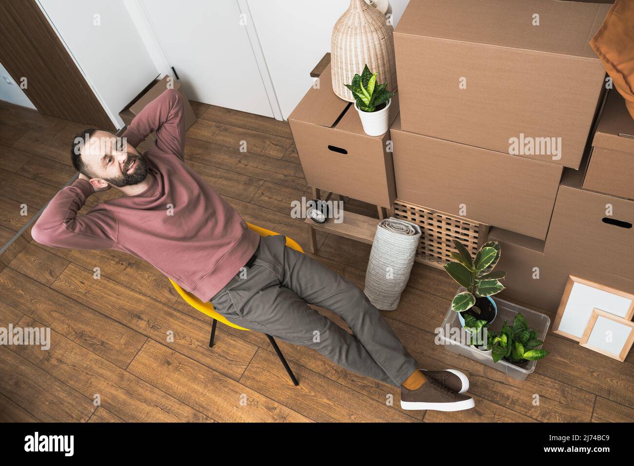 Uomo maturo che si rilassa in un nuovo appartamento non arredato. Foto Stock
